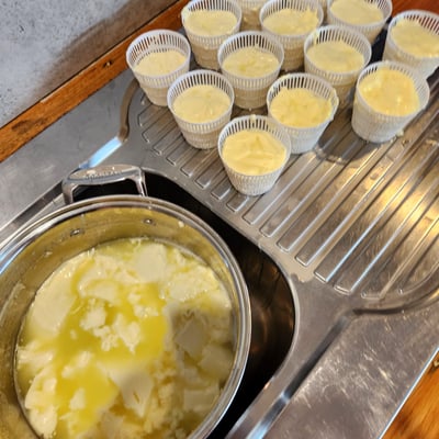 Curds in a pot beside cheese baskets