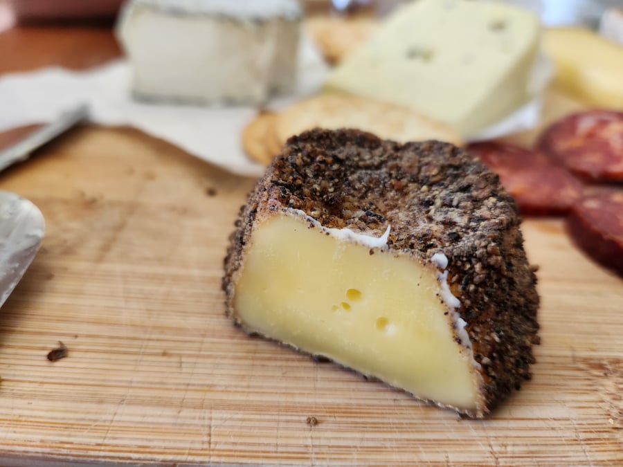 Peppered goat's cheese cut open on a board